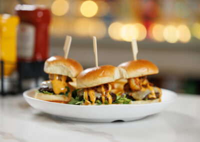 white plated The Quarry restaurant sliders spicy sauce and blurred bar background