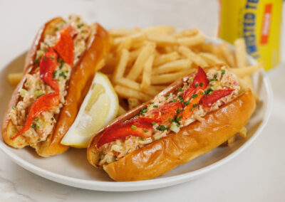 Lobster Roll Sliders with fries on a white plate with lemon and twisted tea