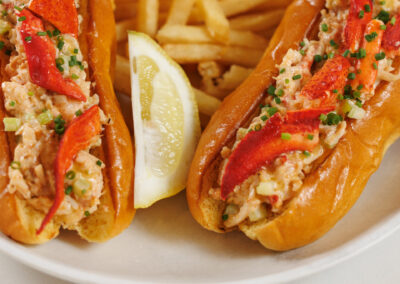 Lobster Roll Sliders with fries on a white plate on a marbled bar